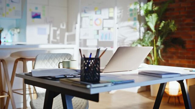 Empty desk open laptop papers coffee mug. Slow pull back modern home work space.