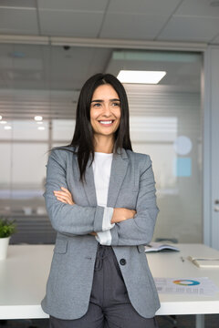 Office portrait of smiling businesswoman, headhunter posing with arms-crossed in meeting room, represents human resources, company employment, executive position, career growth, business opportunities