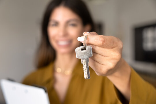 Female realtor agent holding set of keys, as symbol of real estate offer, represents professional services of property selling and buying, new house purchase, rental agreement, bank mortgage, closeup
