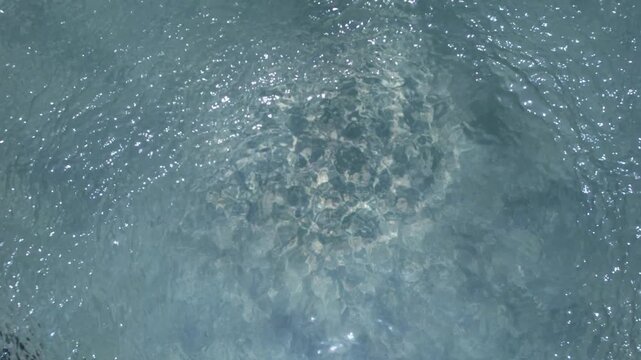 Moving water surface with light reflections and natural texture from above
