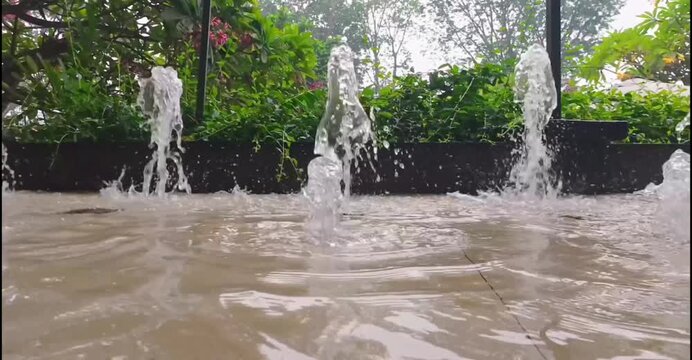 Small decorative water fountain jets sprouting in outdoor garden pool
