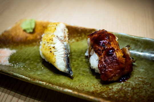 Closeup of traditional Japanese nigiri sushi showing anago sea eel lightly seared and grilled unagi freshwater eel glazed in dark sweet tare sauce. 