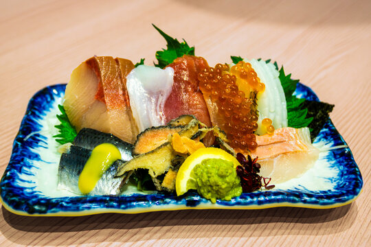Assorted fresh Japanese sashimi with yellowtail (hamachi, tuna, salmon, squid ika, mackerel and abalone garnished with salmon roe ikura, wasabi and shiso leaves.