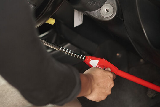Person using a red steering wheel lock inside a vehicle cabin