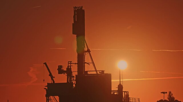 Deep drilling rig silhouetted against a vivid sunrise near R&oslash;dbyhavn during exploration well operations for geological CO2 storage, CCS site characterization and subsurface investigation.