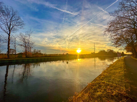 Beautiful sunset casting warm reflections over peaceful waterway with trees