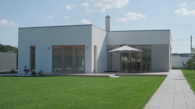 Modern single-story house with a flat roof and white facade.