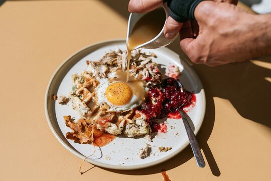 Stuffing waffle with fried egg and turkey leftovers, steaming gravy being poured for a rustic autumn brunch recipe and grocery ad