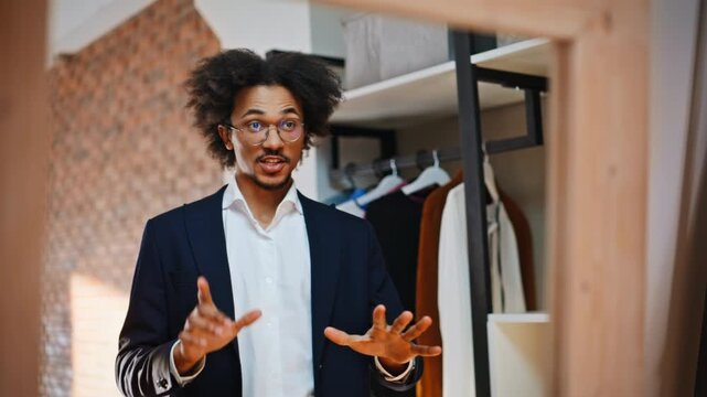Male fashion blogger talking camera wardrobe mirror. Business man gesturing.
