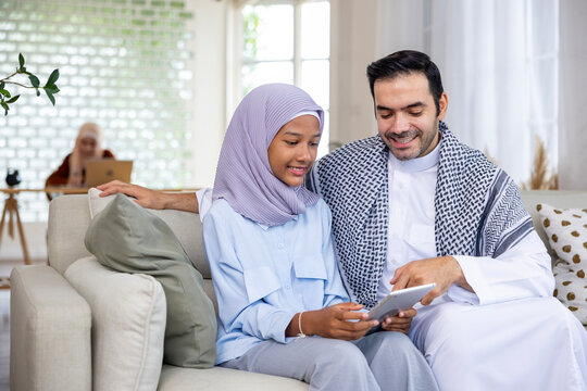 Middle east muslim father is teaching his kid to doing homework and school assignment using digital tablet for online education, social media and ai tool related concept