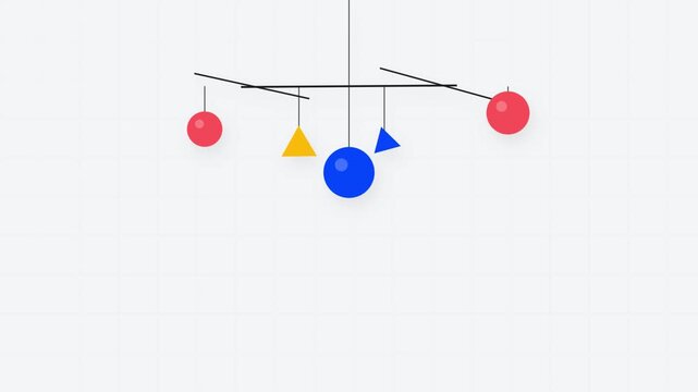 Minimalist mobile hanging sculpture with colorful geometric shapes including spheres and triangles suspended on thin lines against a light background