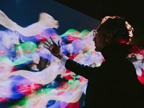 Halloween party people and a man in a vampire cape interacting with glowing neon projections for event promotion and creative concept