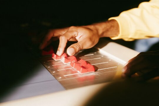 Sound engineer hands adjusting red faders on a mixing console, professional recording studio with copy space for music and broadcasting