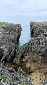 narrow rocky coastal gorge in asturias spain with sea water inlet between steep cliffs