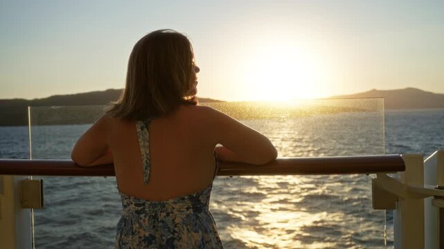 Woman leaning on rail with bare back visible, floral dress strap, hands resting on glass panel of cruise deck at sunset; serenity.