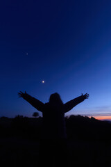 Silhouette of a person in nature observing night sky, Moon, stars and planets from a remote location. © astrosystem