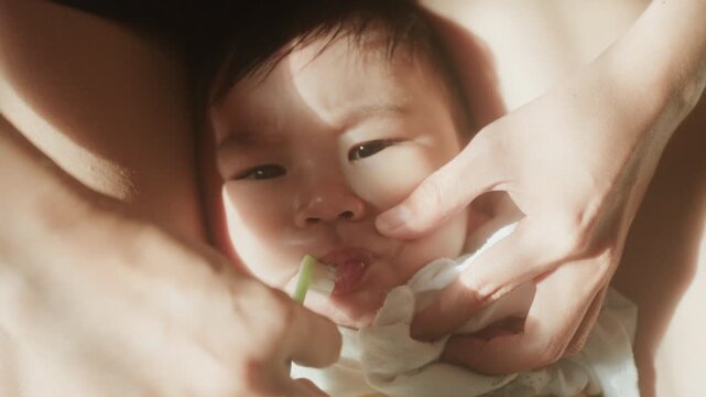 Close up of mother hands cleaning toddler teeth with toothbrush, 4K