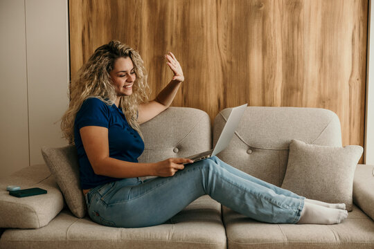Woman waving during video call on laptop at home