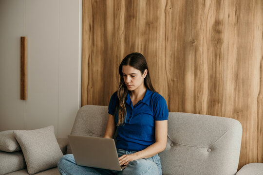 Woman working on laptop from home sofa