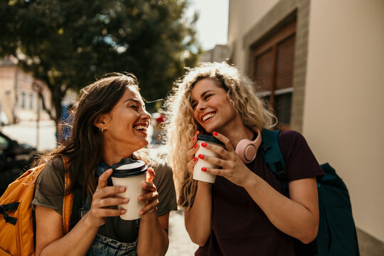 Happy women friends enjoying coffee laughing in city