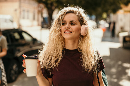 Young woman enjoying music and coffee on city street