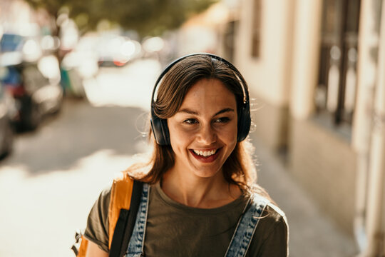 Smiling woman listening to music enjoying city street walk