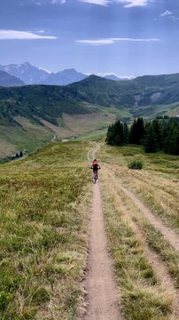 Woman riding electric bike on mountain dirt trail with scenic nature landscape and alpine view