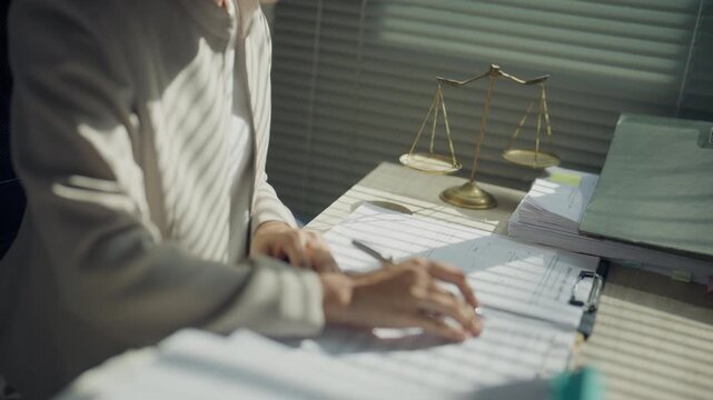 Legal professional reviewing documents at an office desk beside scales of justice, representing legal services, contract review, case preparation, compliance, consultation, and professional law practi