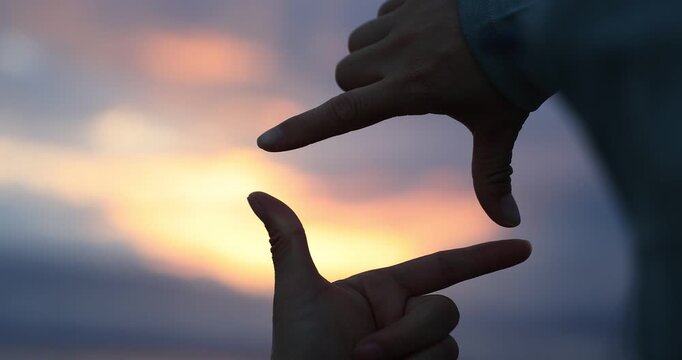 Hands making a picture frame on the sunset seaside