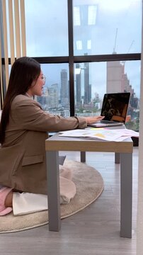 Asian Woman on Video Call at Desk with City View