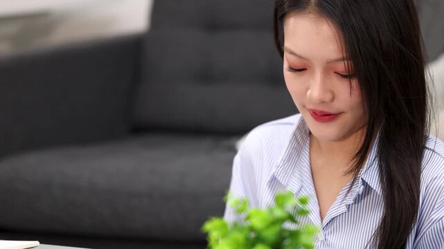 Asian Woman Smiling and Looking Down Indoors in Living Room