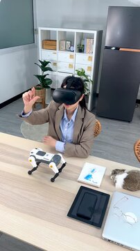 Asian Woman Wearing VR Headset and Gesturing at Office Desk