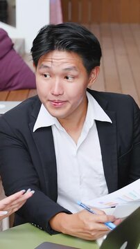 Asian Businessman Discussing Strategy and Reviewing Documents During Team Meeting