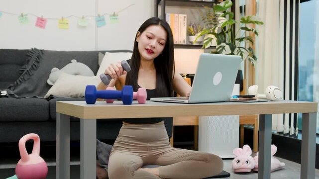Asian Woman Exercising with Dumbbells During Laptop Video Call at Home