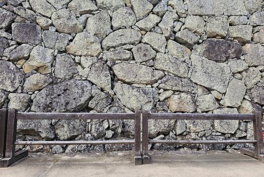 Ancient Himeji Castle stone wall background with wooden fence.