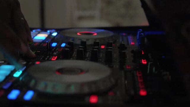 Close Up DJ Hands Mixing Tracks on Illuminated Digital Controller at Night Club Event