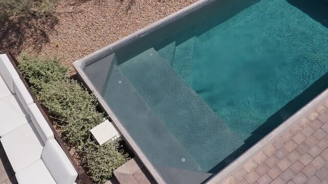 Slow overhead move across submerged steps in a rectangular backyard plunge pool