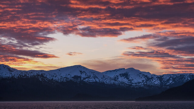 Breathtaking Alaska mountain glacier range view seen from outdoor deck of cruise ship liner sailing the Inside Passage transit with spectacular landscape scenery during sunset