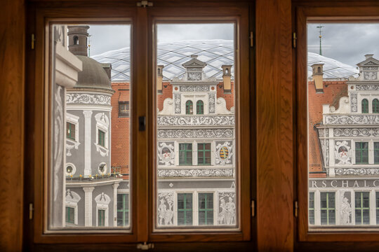 Historic Dresden buildings with sgraffito decoration visible through wooden window panes, Renaissance facade architecture in German Old Town (Altstadt) with ornate white relief patterns and red brick 