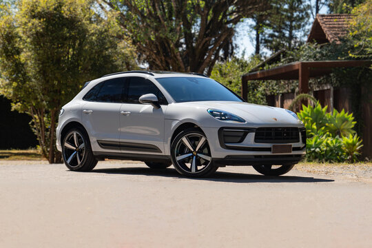 White Porsche Macan Luxury SUV Front Three-Quarter View Parked on Sunny Estate Road Surrounded by Trees