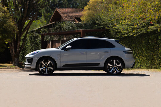 Grey Porsche Macan luxury SUV side view profile parked outdoors near country house garden environment