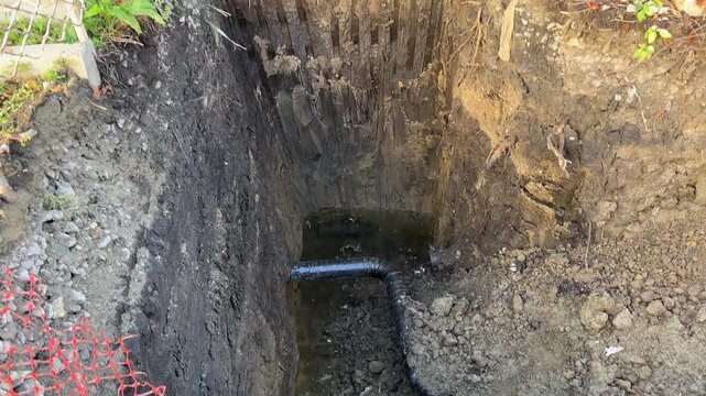 Insulated gas pipe on the very bottom of deep trench. Soil layers, geology. Subsurface laying of engineering utilities