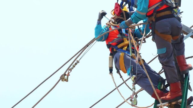 Electrical workers with complete PPE are carrying out cable pulling work using a pulley/hoist machine