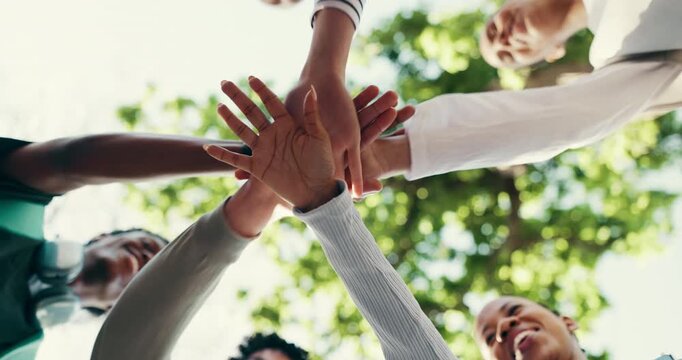 Below, students and hands together in university with motivation, friends or higher education goals. Happy, people and stack outdoor at college with celebration, encouragement or support for learning