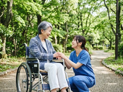 公園で車椅子の高齢者と介護士が笑顔で手を握り心温まる交流
