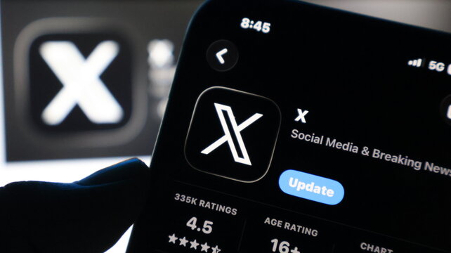 Smartphone screen showing X social media application update page in dark room.