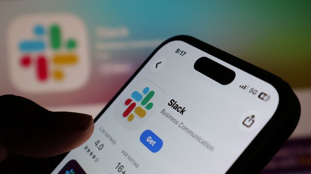 person holding iPhone 14 pro and browsing slack app store page in app store with dynamic island and wifi and battery status.