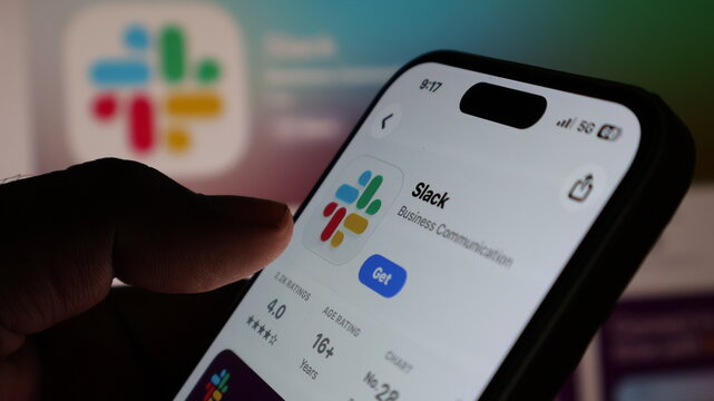 person holding iPhone 14 pro and browsing slack app store page in app store with dynamic island and wifi and battery status.