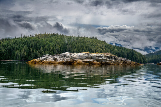Canada, BC, Broughton Archipelago.  A small island reflects in the calm waters on the BC coast.