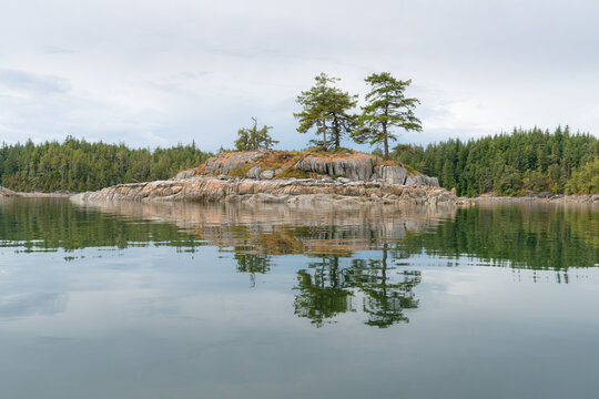Canada, BC, Broughton Archipelago.  A small island reflects in the calm waters on the BC coast.